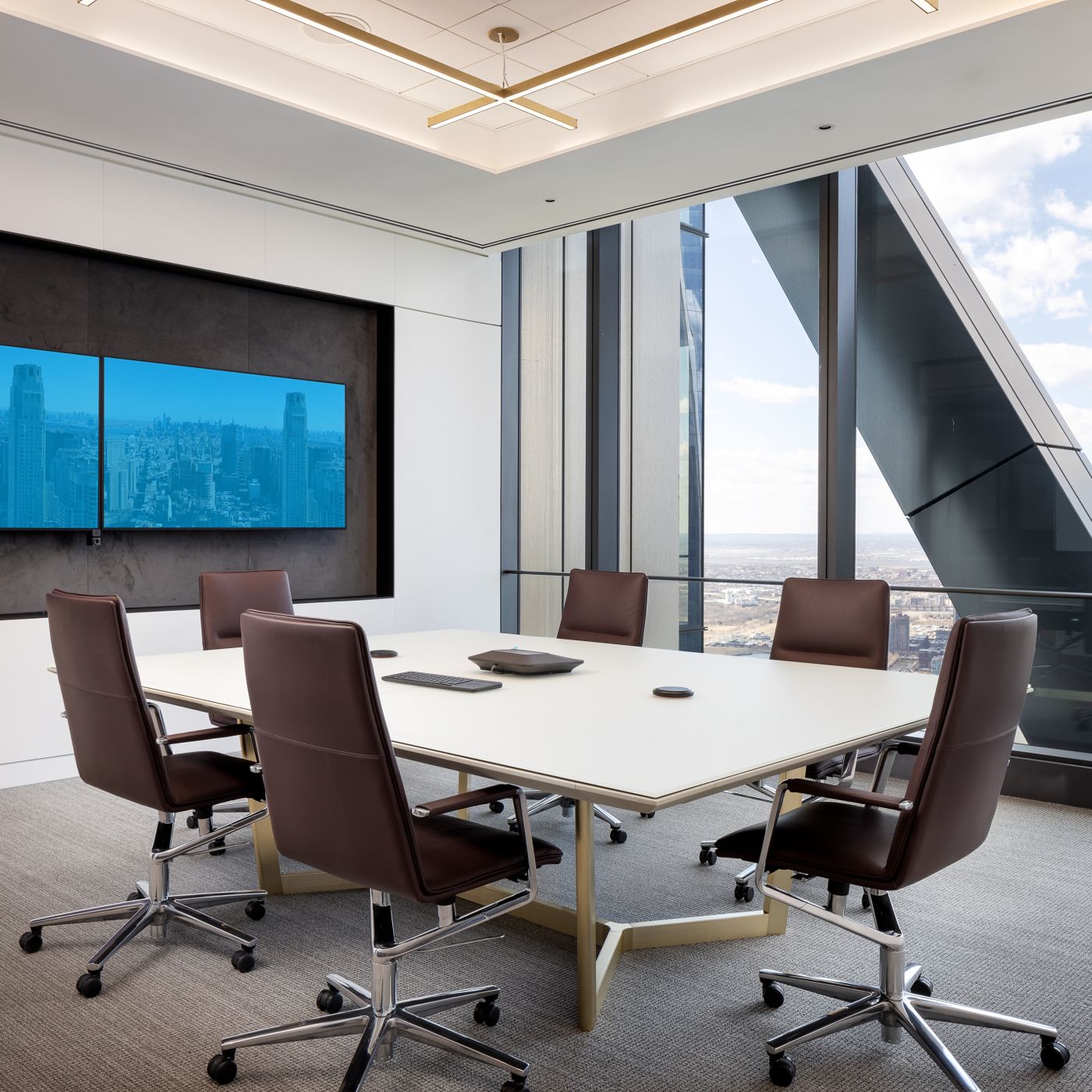 A HALO conference table features an etched glass surface with patented HALO soft edge and Brushed Brass base.